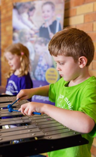 Young boy and girl playing xylophones in music class