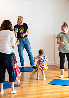 Toddler dancing with teacher and parents in kids music class
